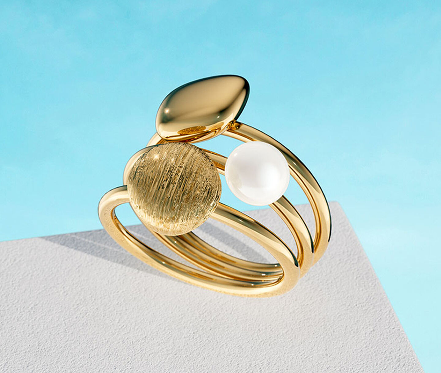 Birks Pebble yellow gold stackable rings on a blue background.